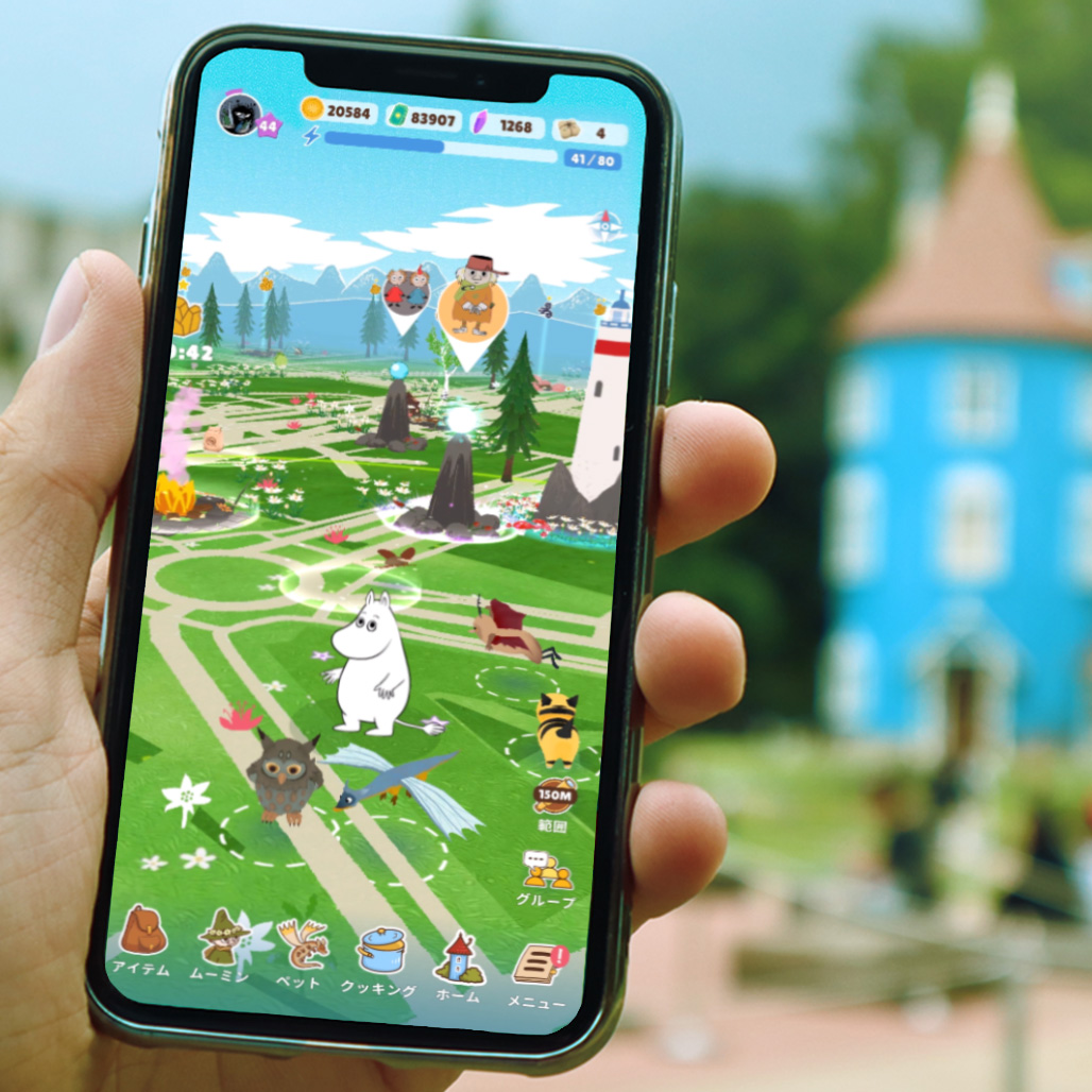 Moomin Move gameplay shown on a phone with the Moominhouse in the background